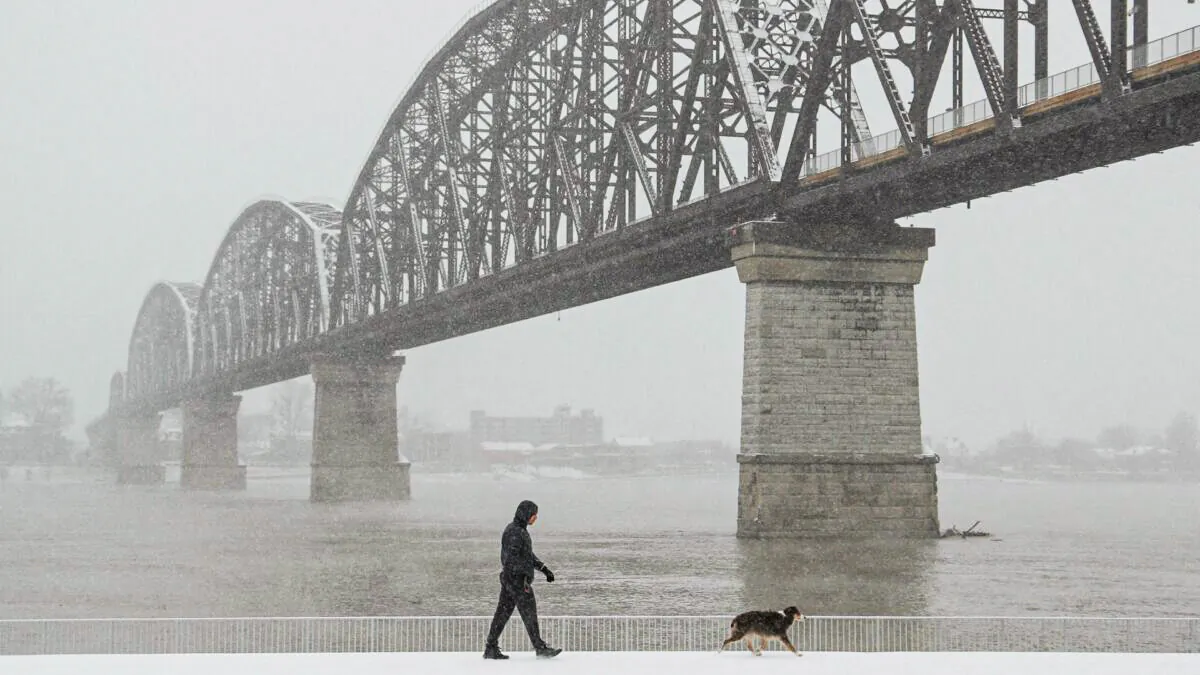 A man walks his dog by the Ohio River, during a snow storm in Louisville, Ky. on Jan. 6, 2022. (Amira Karaoud/Reuters)
