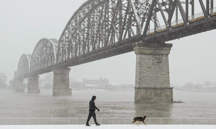 A man walks his dog by the Ohio River, during a snow storm in Louisville, Ky. on Jan. 6, 2022. (Amira Karaoud/Reuters)