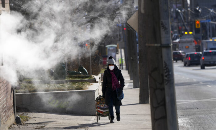 A person walks past steam created from a building vent in the cold weather in Toronto on Jan. 10, 2022. (The Canadian Press/Nathan Denette)