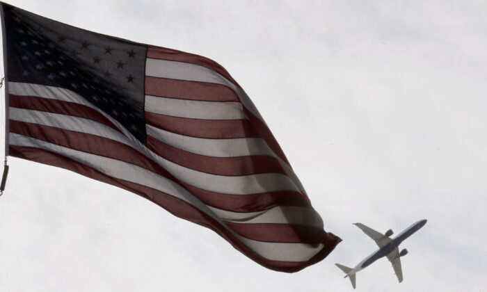 A Delta Airlines flight takes off past a U.S. flag in Boston, Mass., on May 27, 2021.   (Brian Snyder/Reuters)