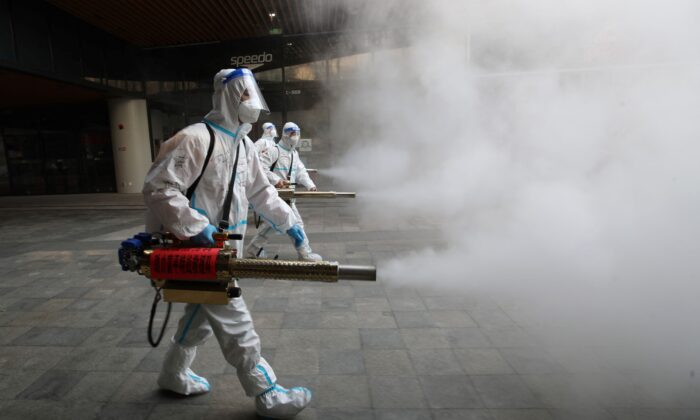 Staff members wearing personal protective equipment spray disinfectant outside a shopping mall in Xi'an, Shaanxi Province, China, on Jan. 11, 2022.
(STR/AFP via Getty Images)