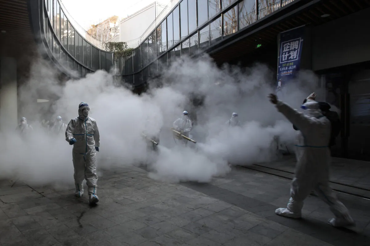 Staff members wearing personal protective equipment (PPE) spray disinfectant outside a shopping mall in Xi'an, China, on Jan. 11, 2022. (STR/AFP via Getty Images)