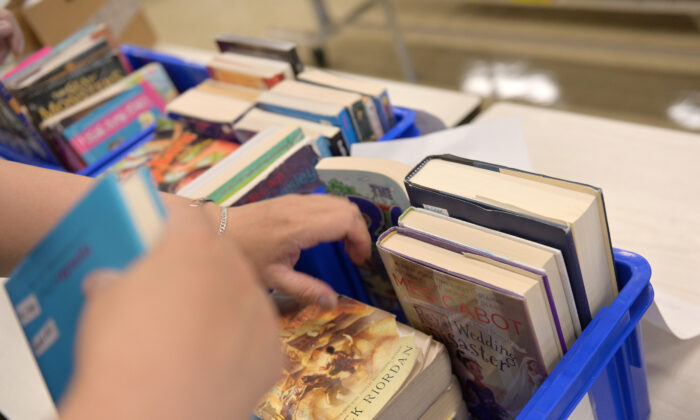 A schoolteacher collects library books from students who just graduated and but borrowed them before schools were shut down at a school in New York on June 29, 2020. (Michael Loccisano/Getty Images)