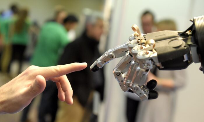 A man moves his finger toward SVH (Servo Electric 5 Finger Gripping Hand) automated hand made by Schunk during the 2014 IEEE-RAS International Conference on Humanoid Robots in Madrid on Nov. 19, 2014. (Gerard Julien/AFP via Getty Images)
