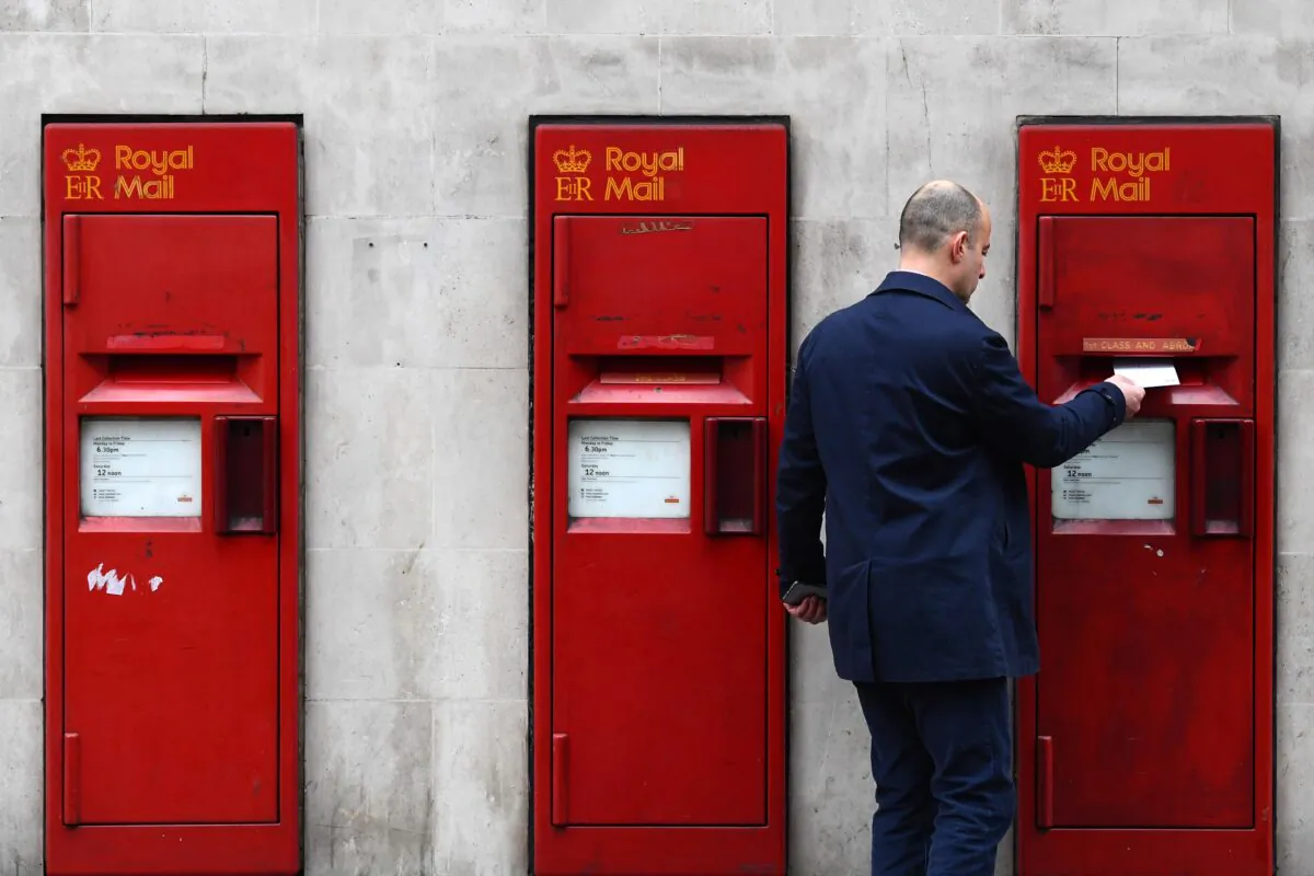 A man posts a letter in a mailbox of a Post Office in London, England on Dec. 19, 2016. (Carl Court/Getty Images)