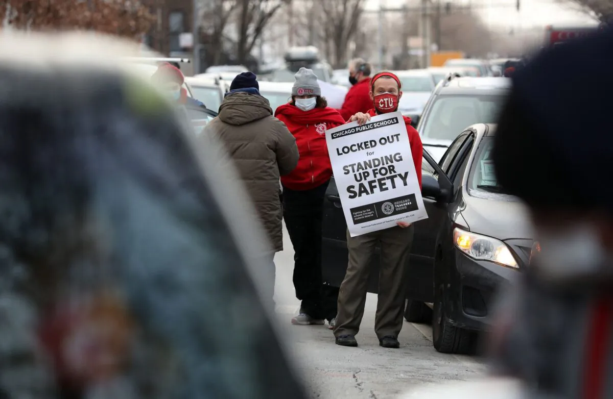Teacher Stuart Abram holds a sign in support of the Chicago Teachers Union before a CTU caravan Wednesday, the first day that classes were canceled amid the dispute over COVID-19 safety measures. (Chicago Tribune via TCA)