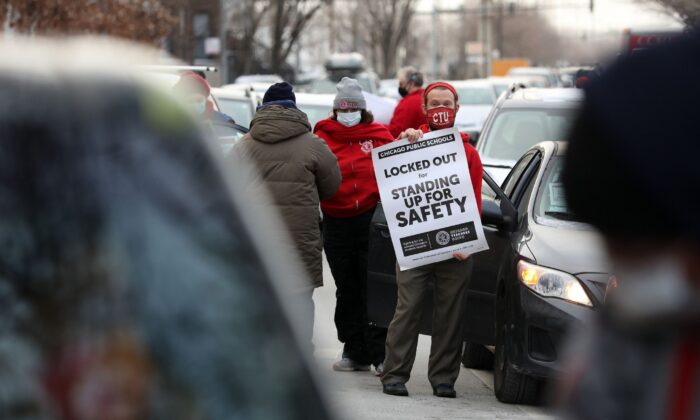 Teacher Stuart Abram holds a sign in support of the Chicago Teachers Union before a CTU caravan Wednesday, the first day that classes were canceled amid the dispute over COVID-19 safety measures. (Chicago Tribune via TCA)