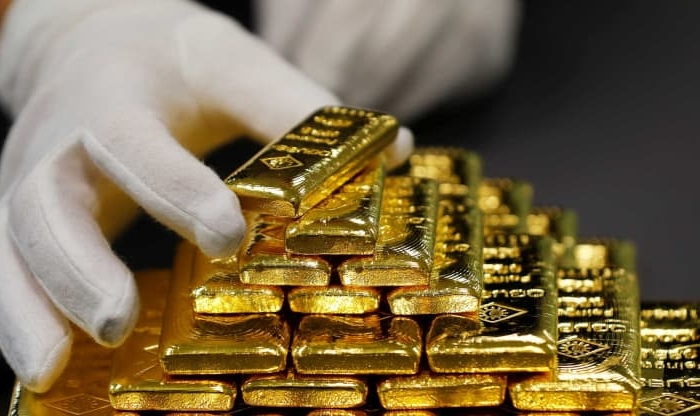 A gloved hand stacks bars of gold into a pyramid. (Leonhard Foeger/Reuters)