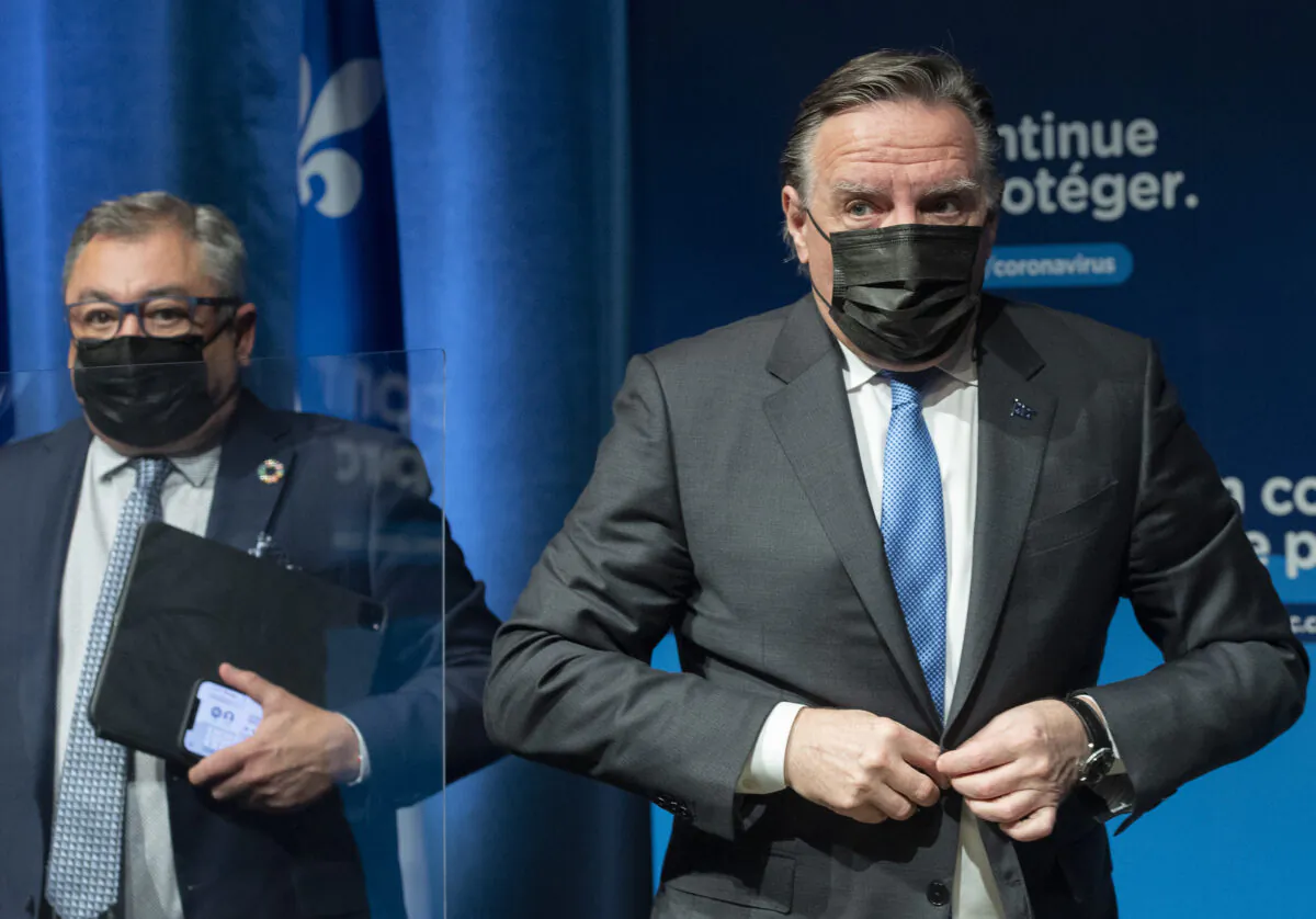 Quebec Premier Francois Legault (R) and then-public health director Horacio Arruda leave a news conference in Montreal on Dec. 30, 2021. (The Canadian Press/Graham Hughes)