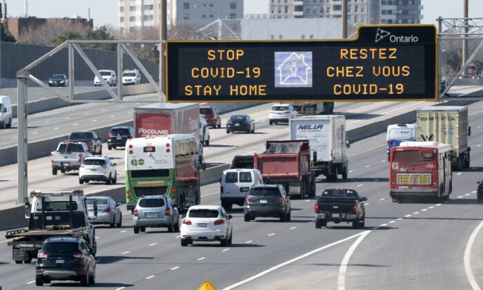 Traffic on Highway 401 in Toronto passes under a COVID-19 sign on April 6, 2020. (The Canadian Press/Frank Gunn)