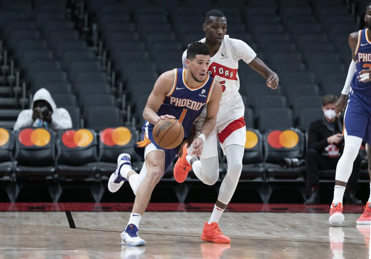 Phoenix Suns guard Devin Booker (1) dribbles the ball, as Toronto Raptors forward Chris Boucher (25) defends during an NBA game at Scotiabank Arena in Toronto on Jan. 11, 2022. (Nick Turchiaro/USA TODAY Sports via Field Level Media)