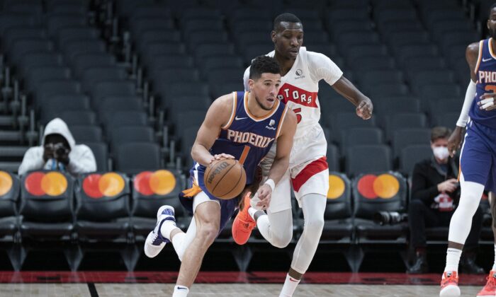 Phoenix Suns guard Devin Booker (1) dribbles the ball, as Toronto Raptors forward Chris Boucher (25) defends during an NBA game at Scotiabank Arena in Toronto on Jan. 11, 2022. (Nick Turchiaro/USA TODAY Sports via Field Level Media)