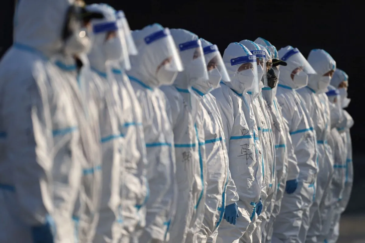 Staff members wearing personal protective equipment prepare to spray disinfectant outside a shopping mall in Xi'an city in north China's Shaanxi Province on Jan. 11, 2022. (STR/AFP via Getty Images)