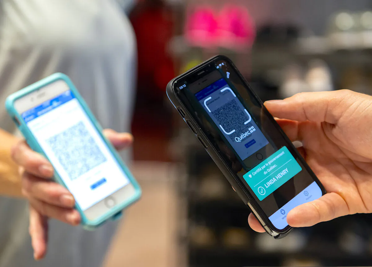 Linda Henry has her COVID-19 QR code scanned by Jonathan Gagne, manager of Orangetheory Fitness in Montreal on Sept. 1, 2021, as the Quebec government’s COVID-19 vaccine passport comes into effect. (The Canadian Press/Graham Hughes)