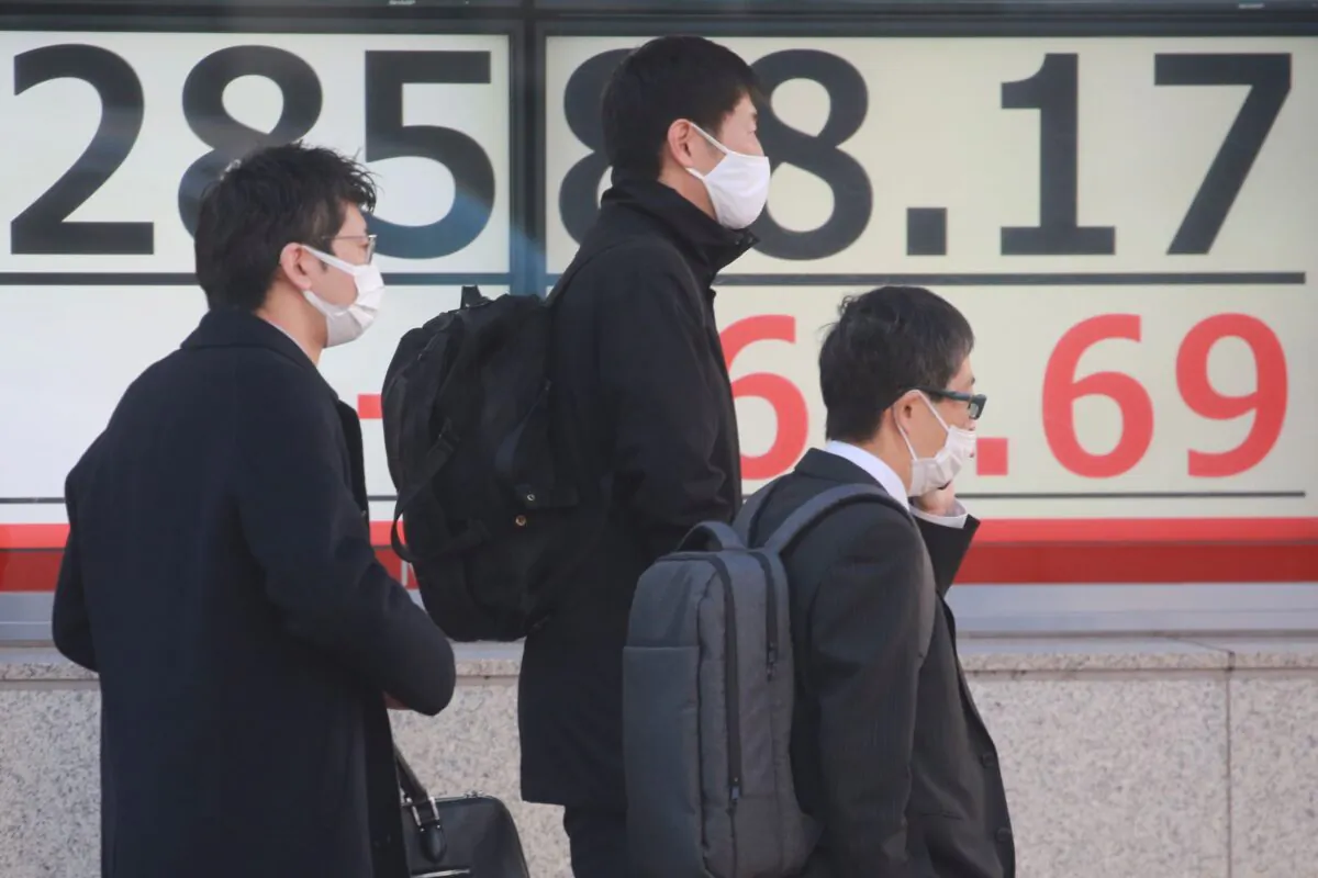 People walk by an electronic stock board of a securities firm in Tokyo, Japan, on Jan. 12, 2022. (Koji Sasahara/AP Photo)