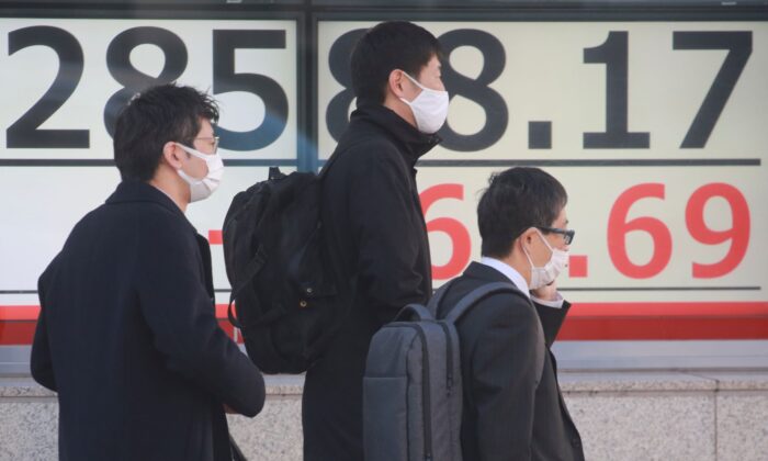 People walk by an electronic stock board of a securities firm in Tokyo, Japan, on Jan. 12, 2022. (Koji Sasahara/AP Photo)