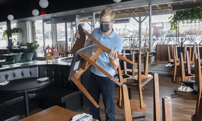A staff member at a restaurant puts chairs on tables ahead of the 5 p.m. curfew in Montreal on Dec. 31, 2021.  (The Canadian Press/Graham Hughes)