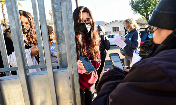 A student shows her negative COVID-19 test result from her cellphone for entry to Olive Vista Middle School on the first day back in Sylmar, Calif., on January 11, 2022. (Frederic J. Brown/AFP via Getty Images)
