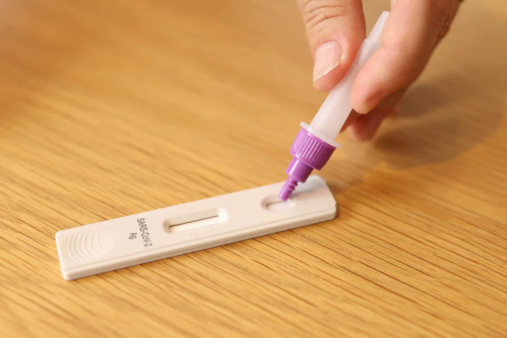 In this photo illustration a man uses a COVID-19 rapid antigen test kit at home in Sydney, Australia on September 29, 2021. (Photo by Cameron Spencer/Getty Images)