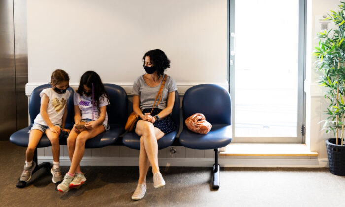 Maria Persic sits with daughters Millie Persic (L) and Sofia Persic during an observation period after the administration of their Pfizer COVID-19 vaccine at Sydney Road Family Medical Practice in Balgowlah, Sydney, Australia on Jan. 11, 2022. (Photo by Jenny Evans/Getty Images)