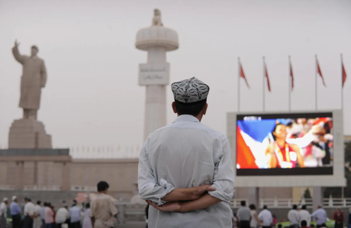 An ethnic Uyghur watches the opening ceremony of the 2008 Beijing Olympic Games on a big screen in the main square in the city of Kashgar, Xinjiang, on Aug. 8, 2008. (Peter Parks/AFP via Getty Images)
