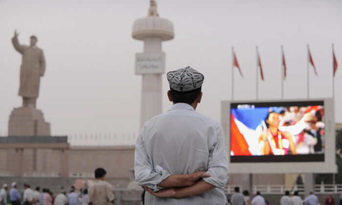 An ethnic Uyghur watches the opening ceremony of the 2008 Beijing Olympic Games on a big screen in the main square in the city of Kashgar, Xinjiang, on Aug. 8, 2008. (Peter Parks/AFP via Getty Images)