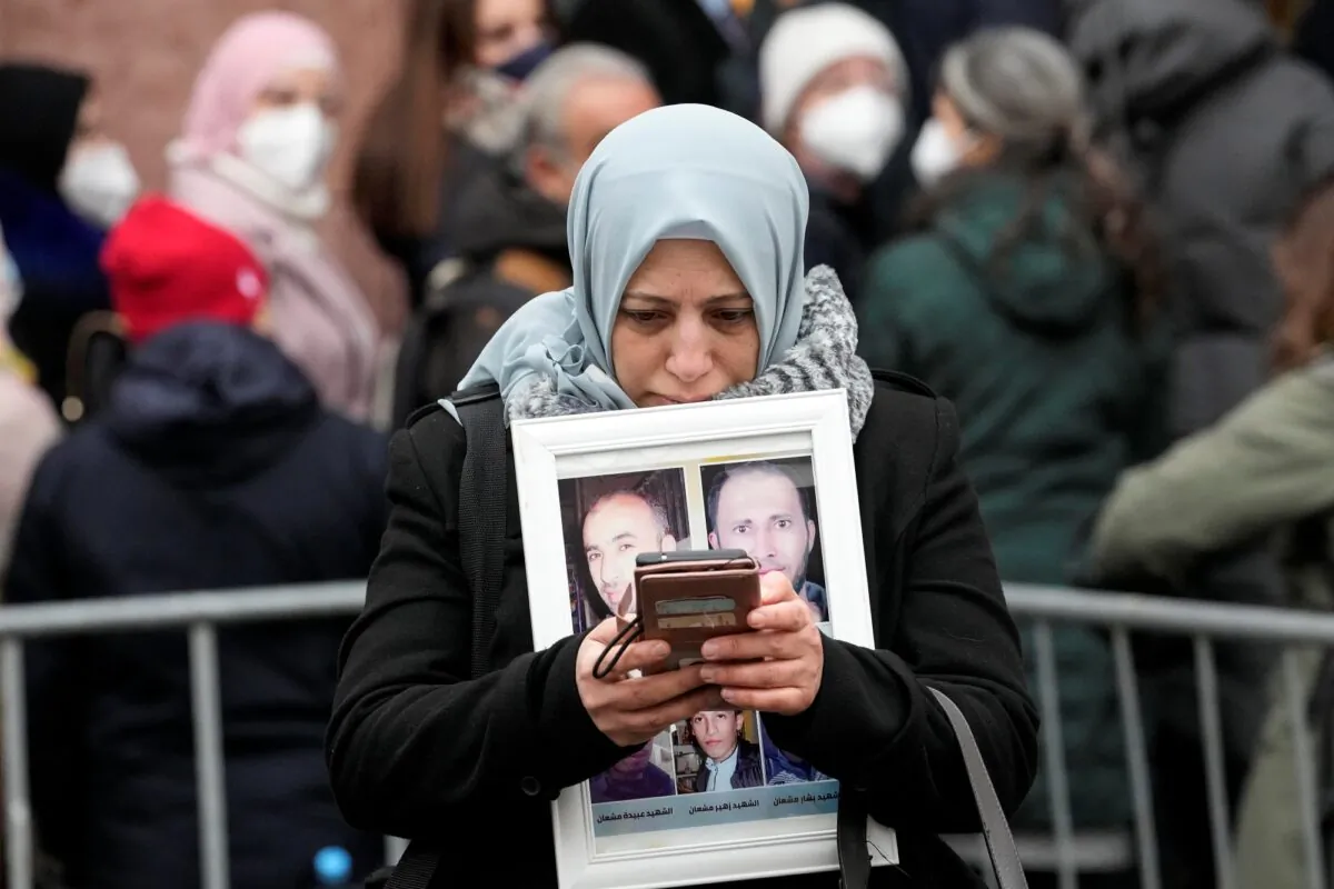 Syrian woman Yasmen Almashan holds the pictures of her five in Syria died brothers before the verdict in front of the court in Koblenz, Germany, on Jan. 13, 2022. (Martin Meissner/AP Photo)