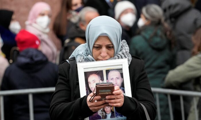 Syrian woman Yasmen Almashan holds the pictures of her five in Syria died brothers before the verdict in front of the court in Koblenz, Germany, on Jan. 13, 2022. (Martin Meissner/AP Photo)