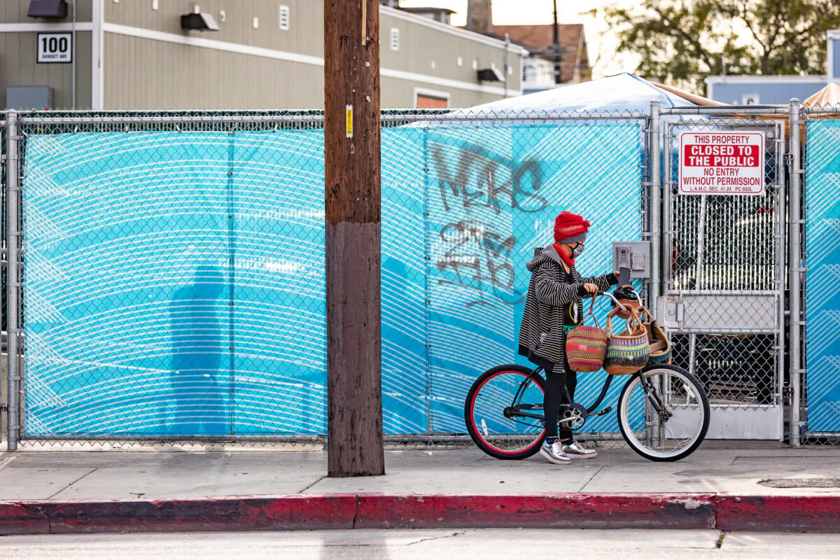 A woman sits on a bicycle near a homeless outreach center in Venice Beach, Calif., on Jan. 27, 2021. (John Fredricks/The Epoch Times)