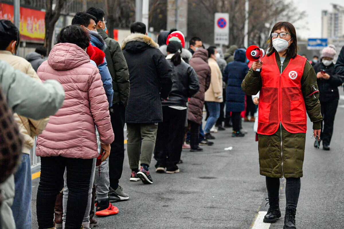 A woman uses a loudspeaker to give advice to residents as they line up during a mass testing in Tianjin, China on Jan. 9, 2022. (Sun Fanyue/Xinhua via AP)