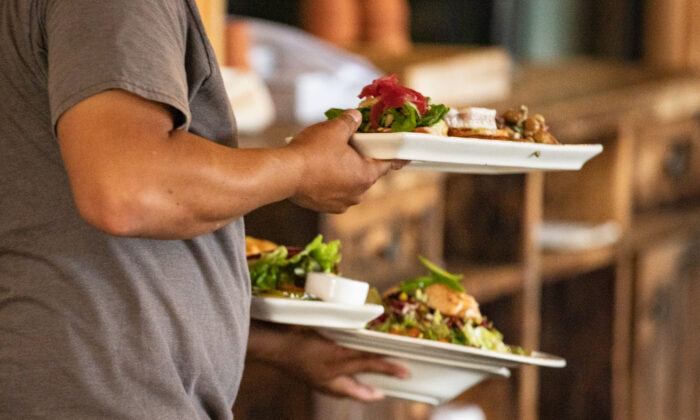 A waiter carries food at The Farmhouse restaurant in Newport Beach, Calif., on Sept. 9, 2020. (John Fredricks/The Epoch Times)