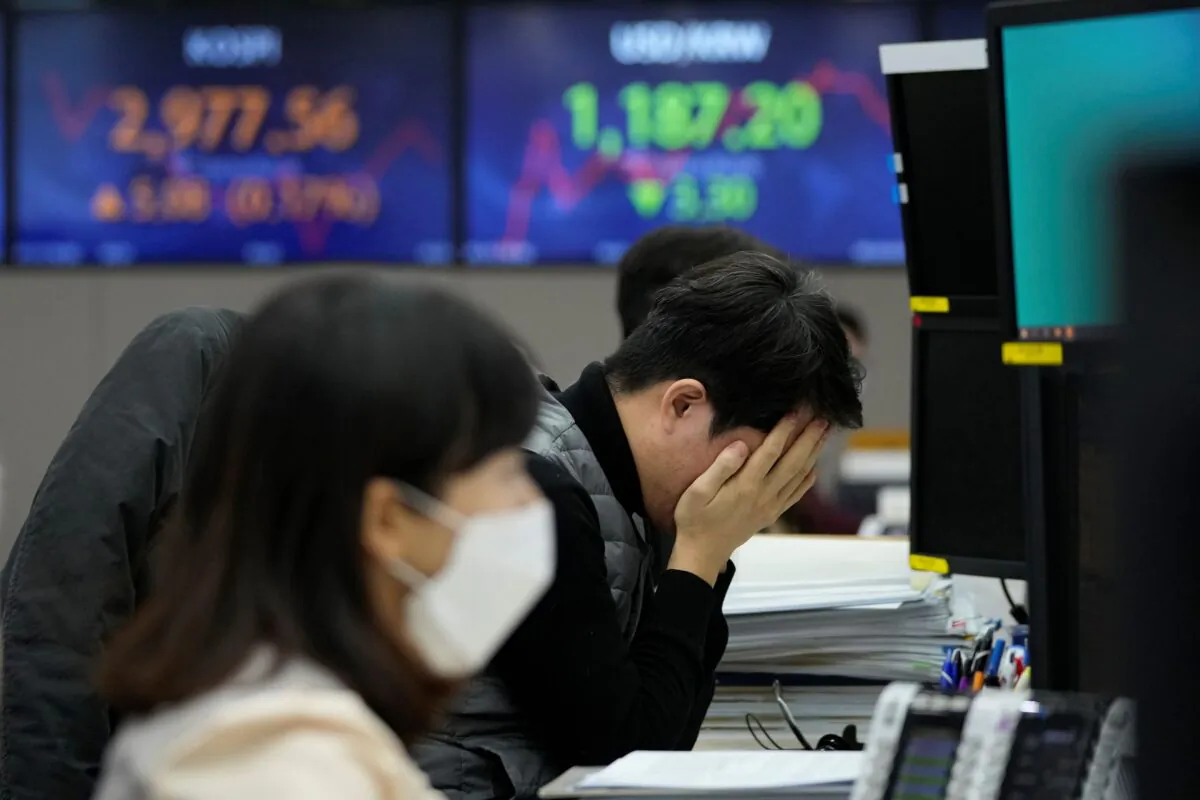 A currency trader covers his face with his hands at the foreign exchange dealing room of the KEB Hana Bank headquarters in Seoul, South Korea, on Jan. 13, 2022. (Ahn Young-joon/AP Photo)