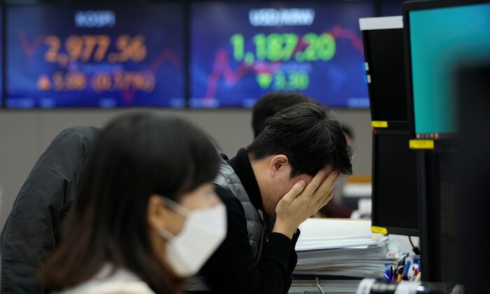 A currency trader covers his face with his hands at the foreign exchange dealing room of the KEB Hana Bank headquarters in Seoul, South Korea, on Jan. 13, 2022. (Ahn Young-joon/AP Photo)
