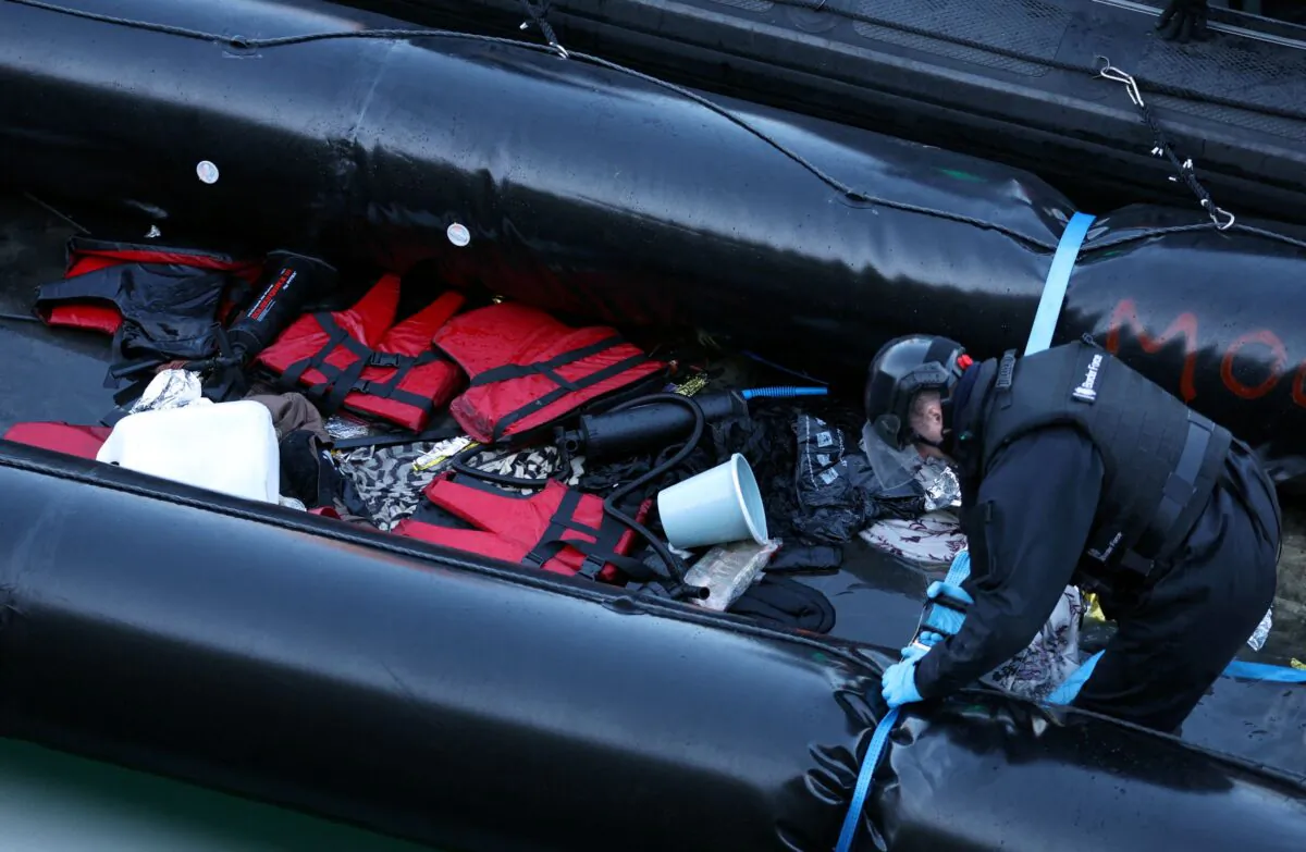 A British Border Force staff member inspects a dinghy used by migrants at Dover harbour, in Dover, Britain, on Jan. 14, 2022. (Hannah McKay/Reuters)