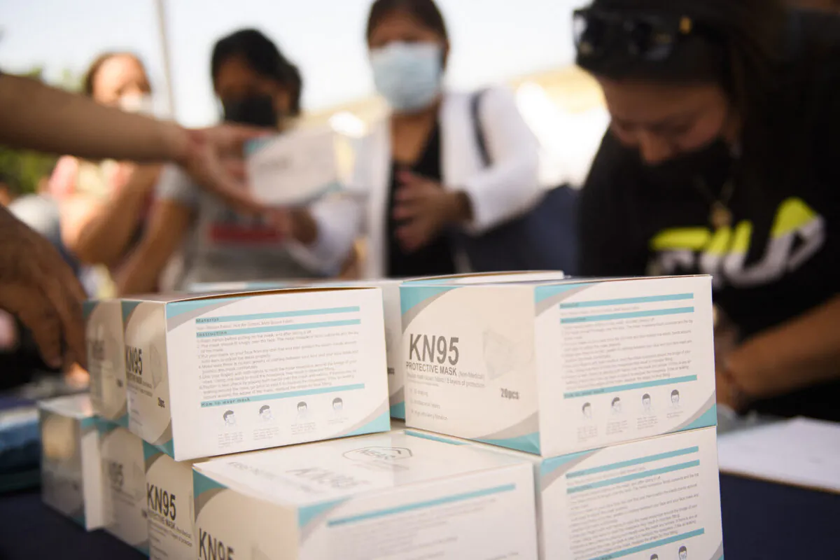 People receive boxes of KN95 face mask during a back to school event offering school supplies, Covid-19 vaccinations, face masks, and other resources for children and their families at the Weingart East Los Angeles YMCA in Los Angeles, California on Aug. 7, 2021. (Patrick T. Fallon/AFP via Getty Images)