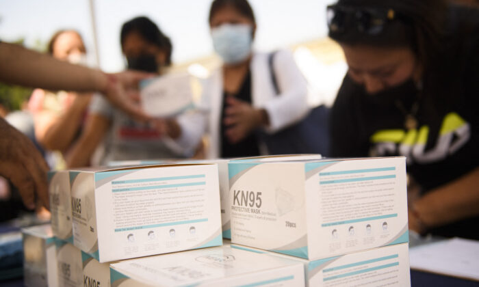 People receive boxes of KN95 face mask during a back to school event offering school supplies, Covid-19 vaccinations, face masks, and other resources for children and their families at the Weingart East Los Angeles YMCA in Los Angeles, California on Aug. 7, 2021. (Patrick T. Fallon/AFP via Getty Images)