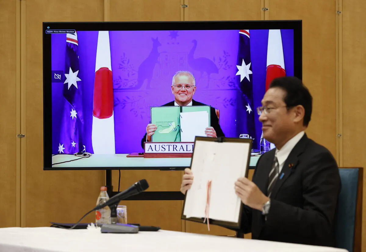 Japan's Prime Minister Fumio Kishida (R) and Australia's Prime Minister Scott Morrison hold signed documents during their video signing ceremony of the bilateral reciprocal access agreement at Kishida's official residence in Tokyo on Jan. 6, 2022. (Issei Kato/POOL/AFP via Getty Images)
