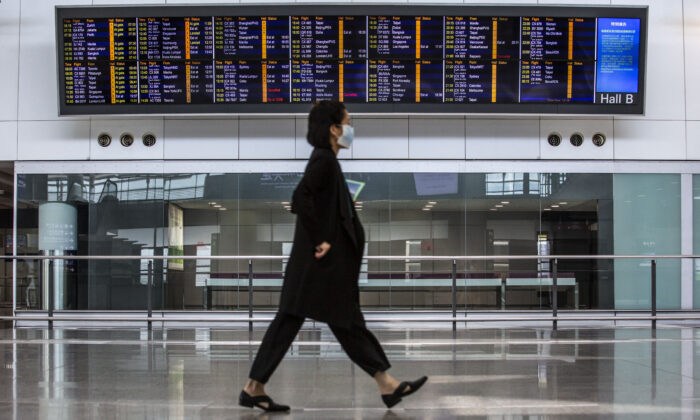 A women walks past a flight information board at Hong Kong International Airport, on Aug. 11, 2021. (Isaac Lawrence/AFP via Getty Images)