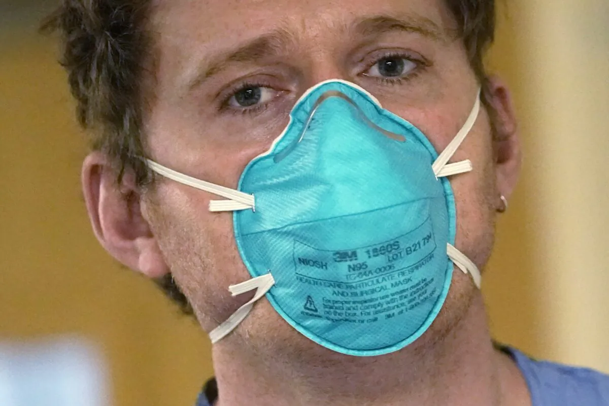 Registered nurse Scott McGieson wears an N95 mask as he walks out of a patient's room in the acute care unit of Harborview Medical Center in Seattle, on Jan. 14, 2022. (Elaine Thompson/AP Photo)