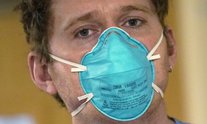Registered nurse Scott McGieson wears an N95 mask as he walks out of a patient's room in the acute care unit of Harborview Medical Center in Seattle, on Jan. 14, 2022. (Elaine Thompson/AP Photo)