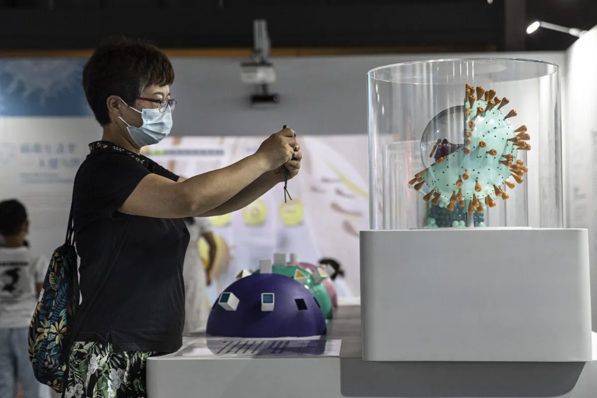A woman wears a mask while taking pictures of the COVID-19 virus model on display at the “Enlightenment of COVID-19” science exhibition in Wuhan Natural History Museum, in Wuhan, Hubei Province, China, on July 18, 2021. (Getty Images)