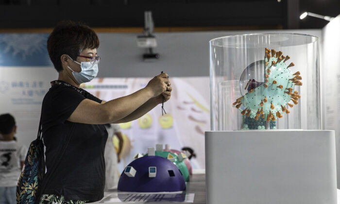 A woman wears a mask while taking pictures of the COVID-19 virus model on display at the “Enlightenment of COVID-19” science exhibition in Wuhan Natural History Museum, in Wuhan, Hubei Province, China, on July 18, 2021. (Getty Images)