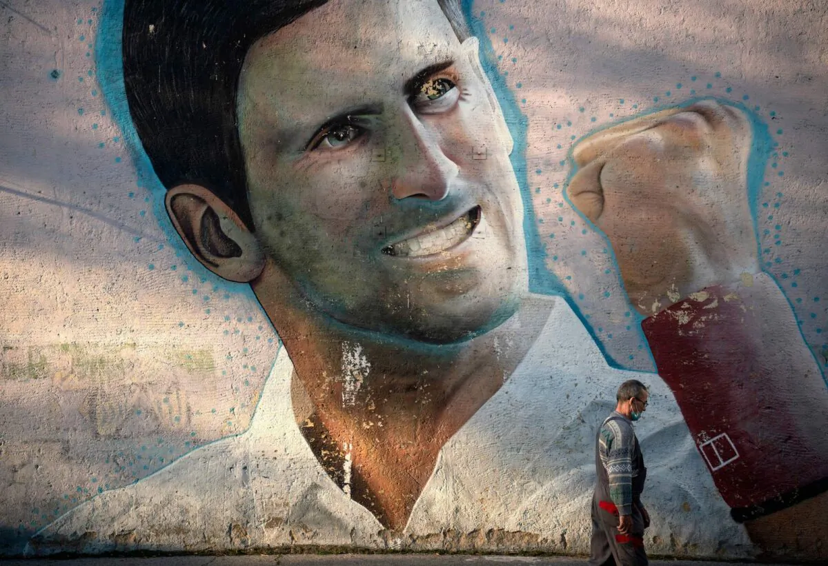 A man walks past a mural depicting Serbian tennis player Novak Djokovic, painted on the external wall of a primary school, in Belgrade, Serbia, on Jan. 14, 2022. (Oliver Bunic/AFP via Getty Images)