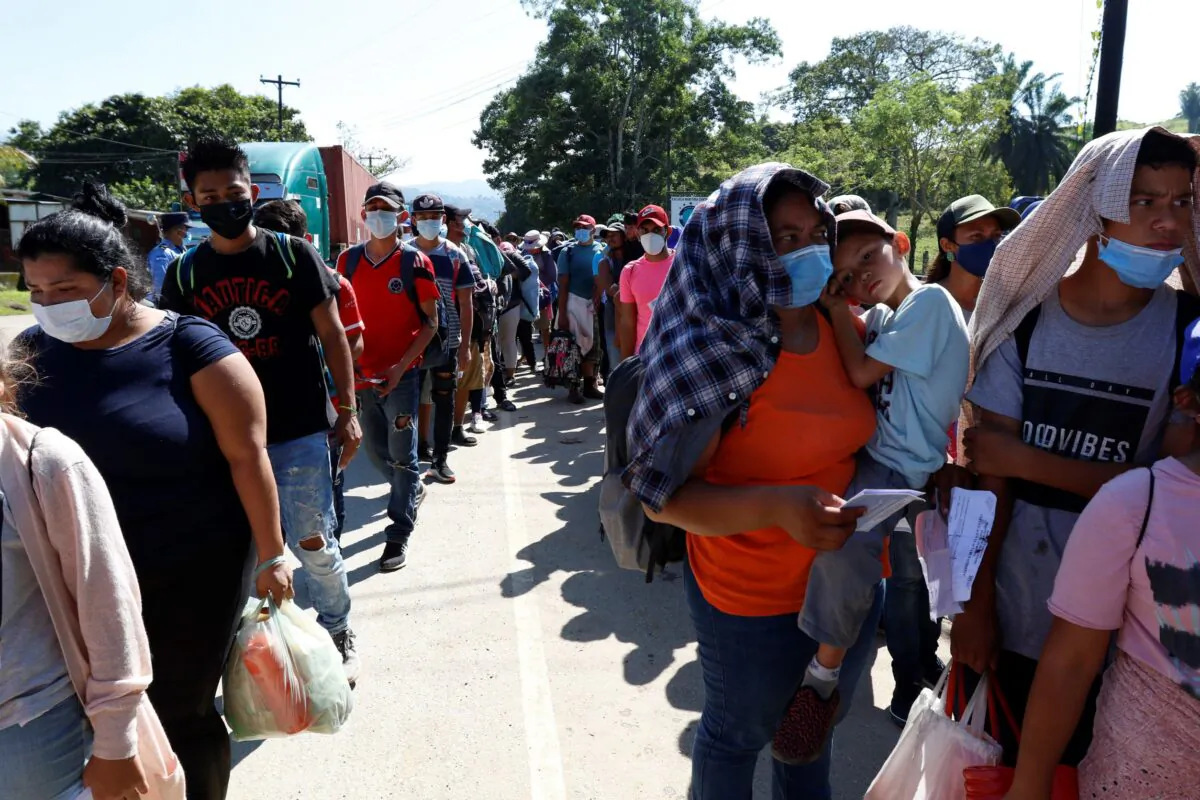 Migrants who are part of a caravan hoping to reach the United States, wait in a line as they wait to have their documents checked by police in Corinto, Honduras, on Jan. 15, 2022. (Delmer Martinez/AP Photo)