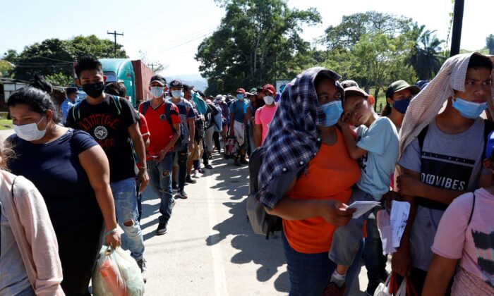 Migrants who are part of a caravan hoping to reach the United States, wait in a line as they wait to have their documents checked by police in Corinto, Honduras, on Jan. 15, 2022. (Delmer Martinez/AP Photo)
