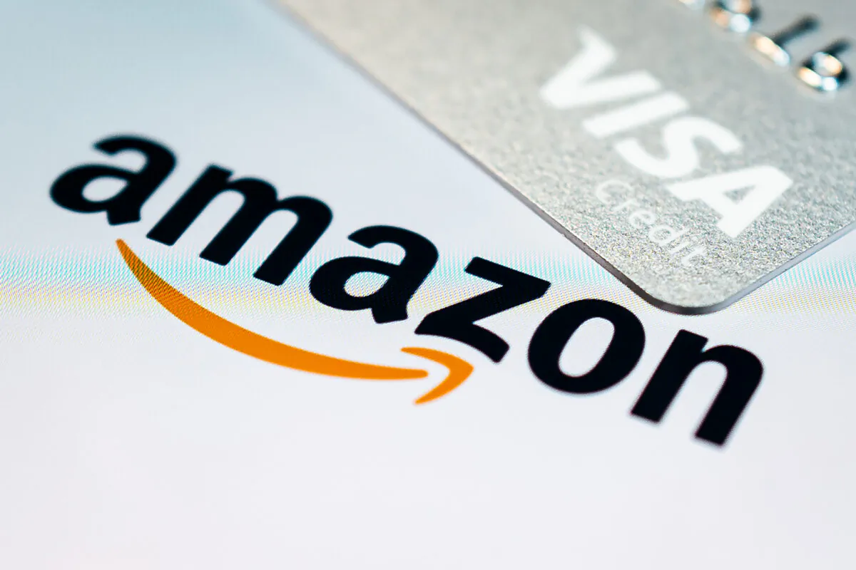 A photo illustration showing a visa credit card above the Amazon logo on the mobile app splash screen in London, on Nov. 17, 2021. (Leon Neal/Getty Images)