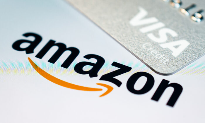 A photo illustration showing a visa credit card above the Amazon logo on the mobile app splash screen in London, on Nov. 17, 2021. (Leon Neal/Getty Images)