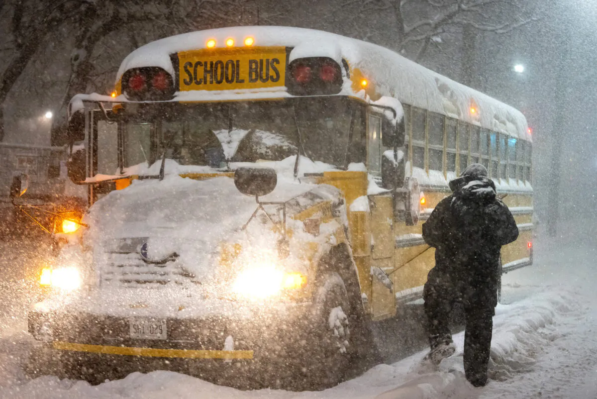A school bus driver tries to clear snow as a winter storm causes the closure of schools in Toronto on January 17, 2022. (The Canadian Press/Frank Gunn)