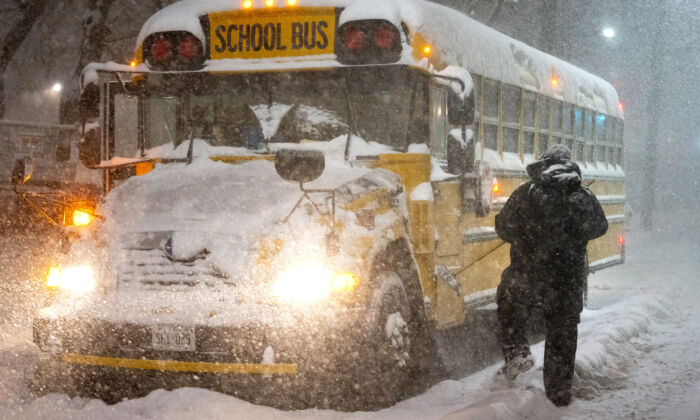 A school bus driver tries to clear snow as a winter storm causes the closure of schools in Toronto on January 17, 2022. (The Canadian Press/Frank Gunn)