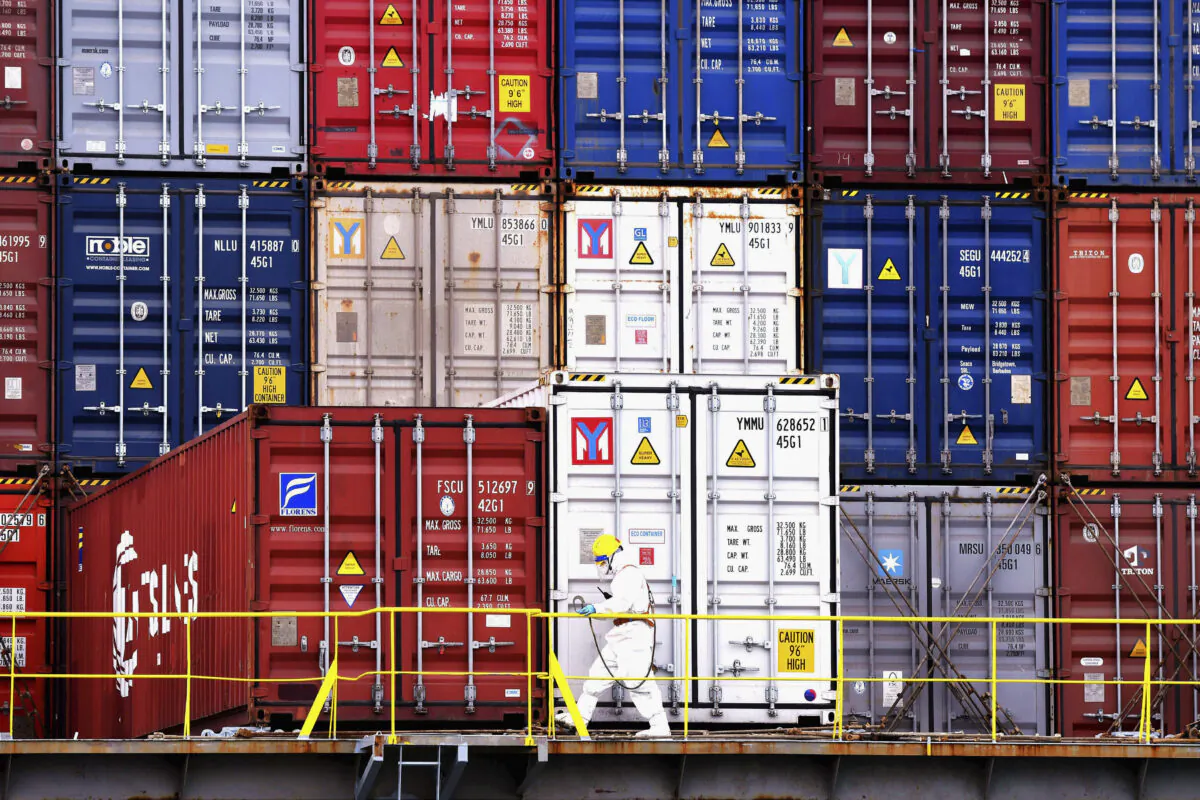 A worker in protective overalls works near containers on a ship in Qingdao city in east China's Shandong Province on Nov. 7, 2021. (Chinatopix via AP)